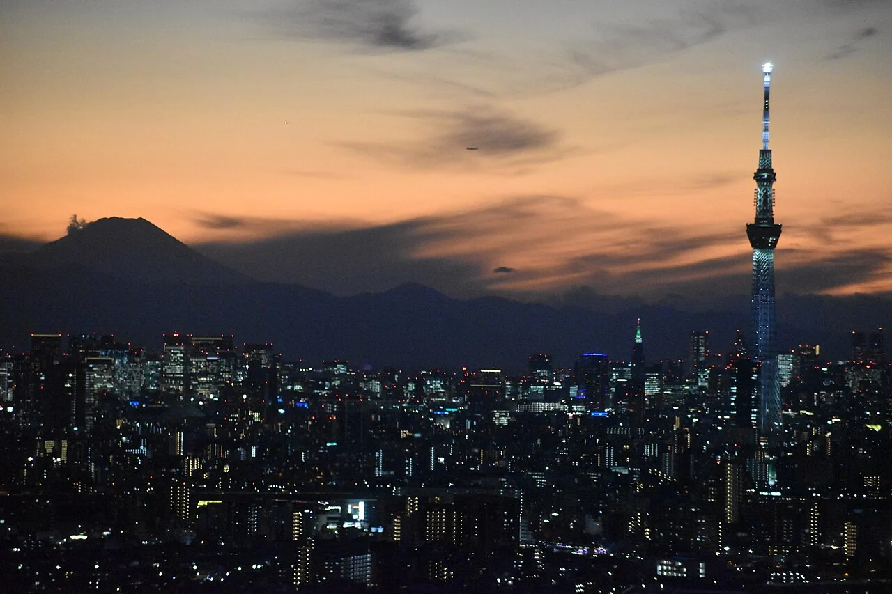 Tokyo skyline at sunset with Mount Fuji visible in the distance.